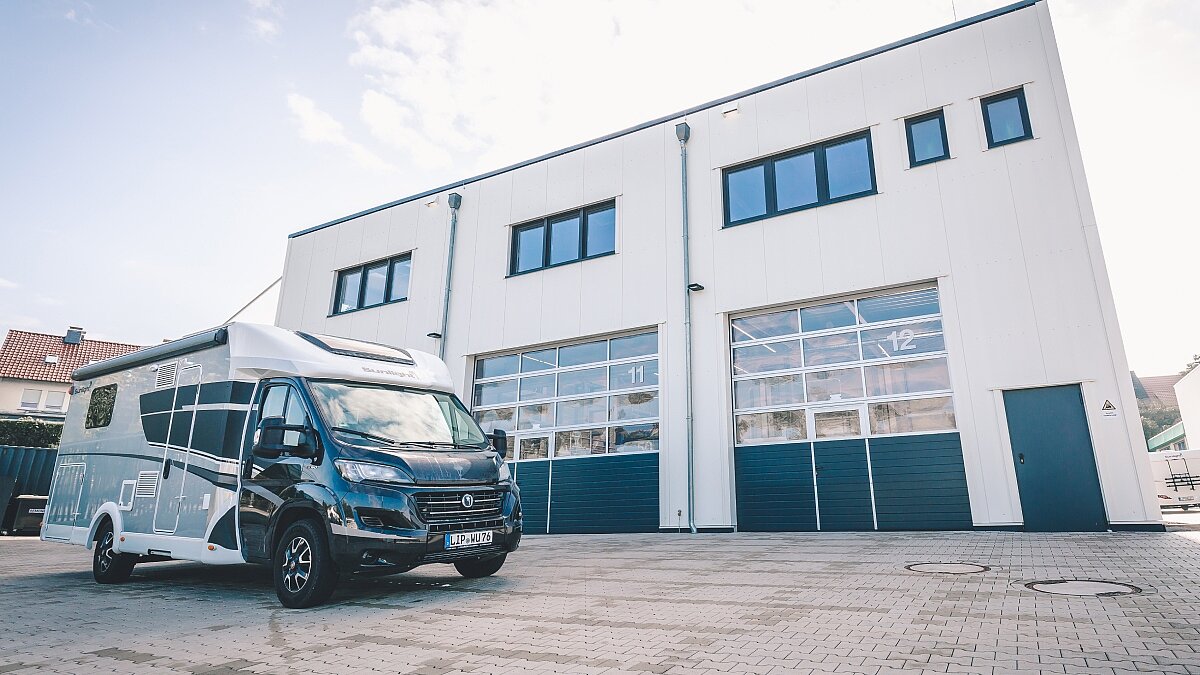 Außenansicht der Werkstatt von Ullrich Caravaning mit Blick auf drei geschlossene Rolltore. Davor ein geparktes Wohnmobil von Sunlight.